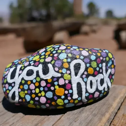 hand painted rock that says you rock on it in cursive surrounded by dots